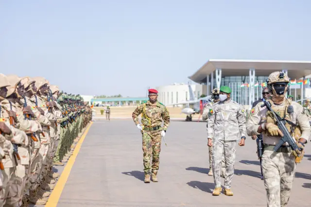 le général assimi goïta, président de la transition au Mali, en tenue militaire, passe en revue des troupes lors d'une cérémonie officielle.