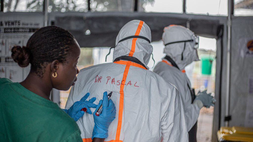 Agent d'hygiène inscrivant le nom d'un médecin sur sa combinaison de protection avant d'entrer dans un centre de traitement Ebola à Bunia, en Ituri